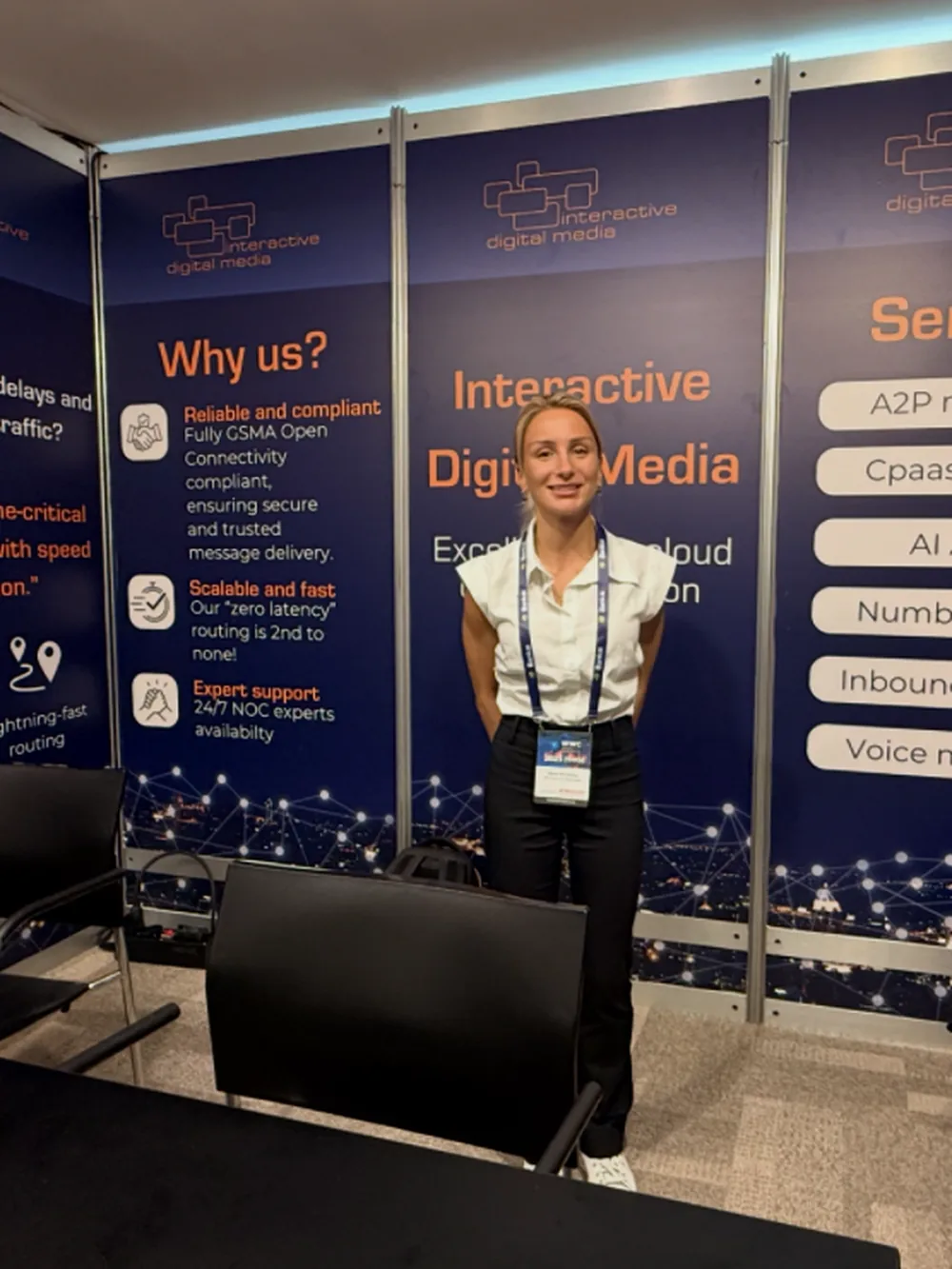 An exhibition stand branded for Interactive Digital Media, with a presenter beside the display